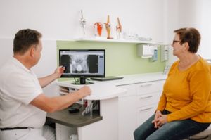 Dr. Schmidt zeigt einer Patientin den Schweregrad Ihrer Hüftarthrose auf