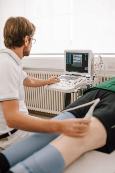 Dr. med. Lutz Müller untersucht einen Patienten mit Hinblick auf eine mögliche Kniearthrose